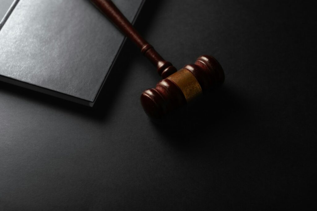 Wooden gavel resting on a dark surface next to a book, representing legal proceedings