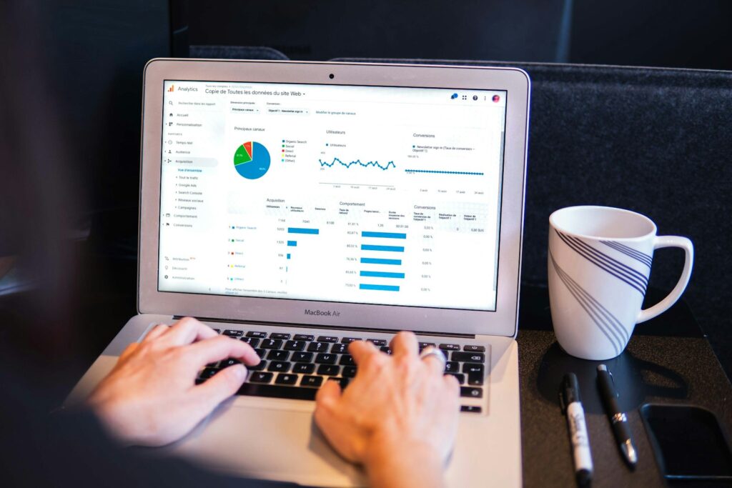 Person using a MacBook Pro showing a Google Analytics overview report, relevant to tracking online advertising