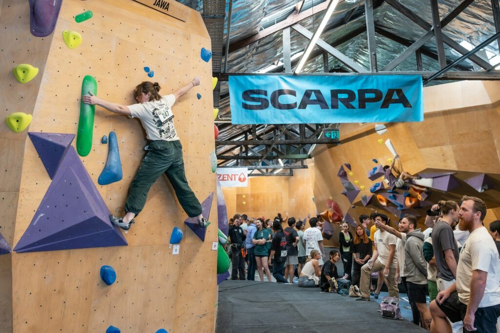 A group of people standing around an indoor climbing wall, ahead of a session where injuries can happen