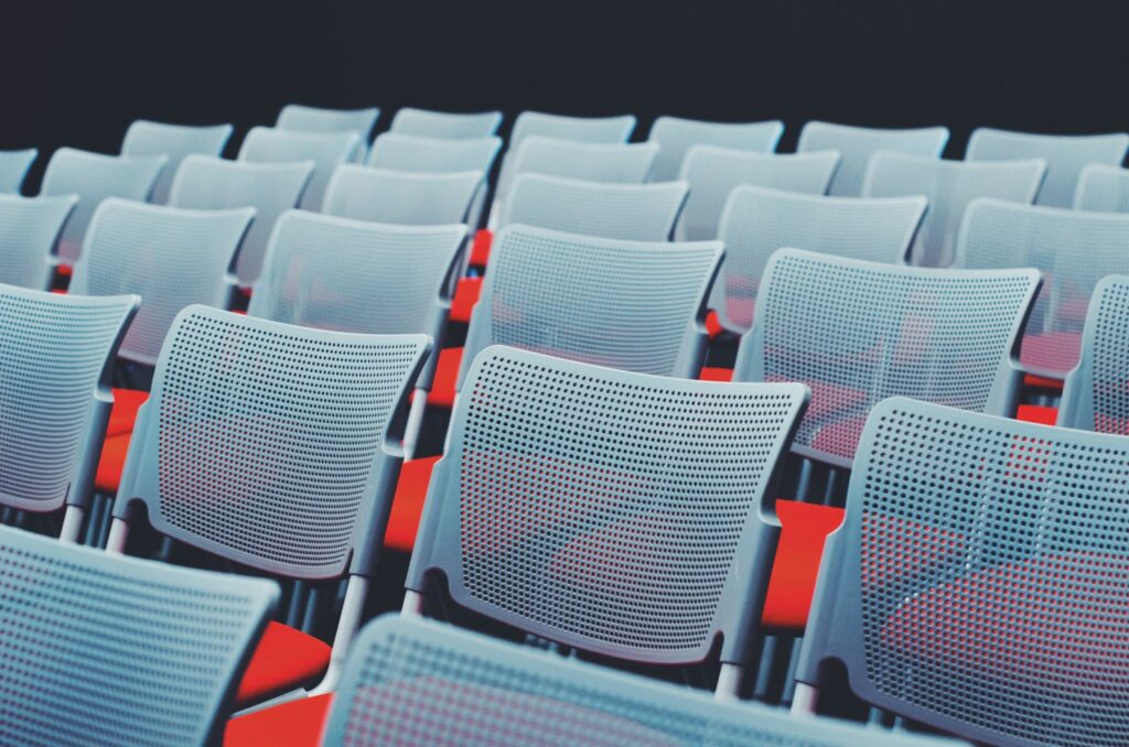 An empty conference room with rows of white chairs, ready to be set up for an event