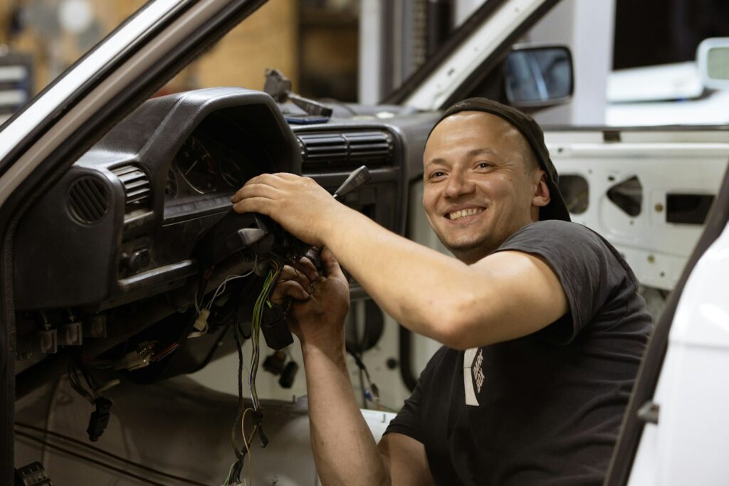 Man in a black t-shirt holding a car steering wheel, relevant to steering column repairs