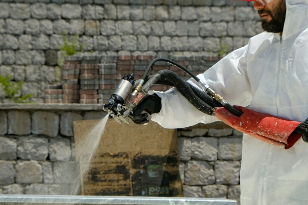 Worker in white coveralls spraying water with a hose, as in safety work on hazardous materials