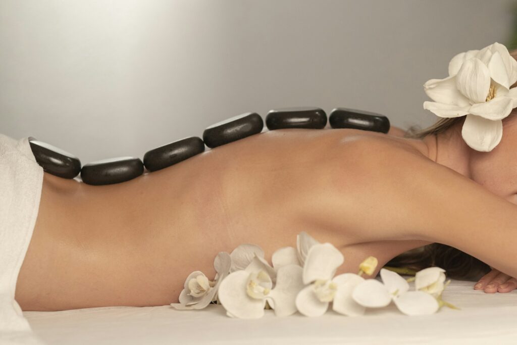 Woman lying on a massage table with smooth black stones placed along her back at a spa