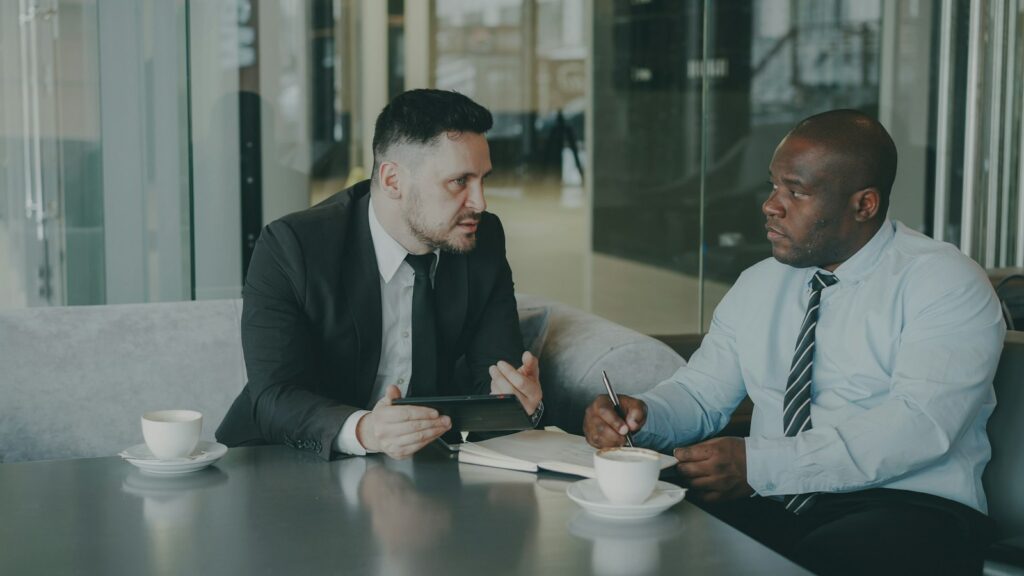 Two businessmen discussing work over coffee, representing mentoring and support for local business owners